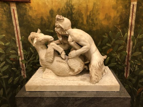 A statue of a satyr on top of a goat. His penis is visible: he is penetrating the goat, who seems fine with it
