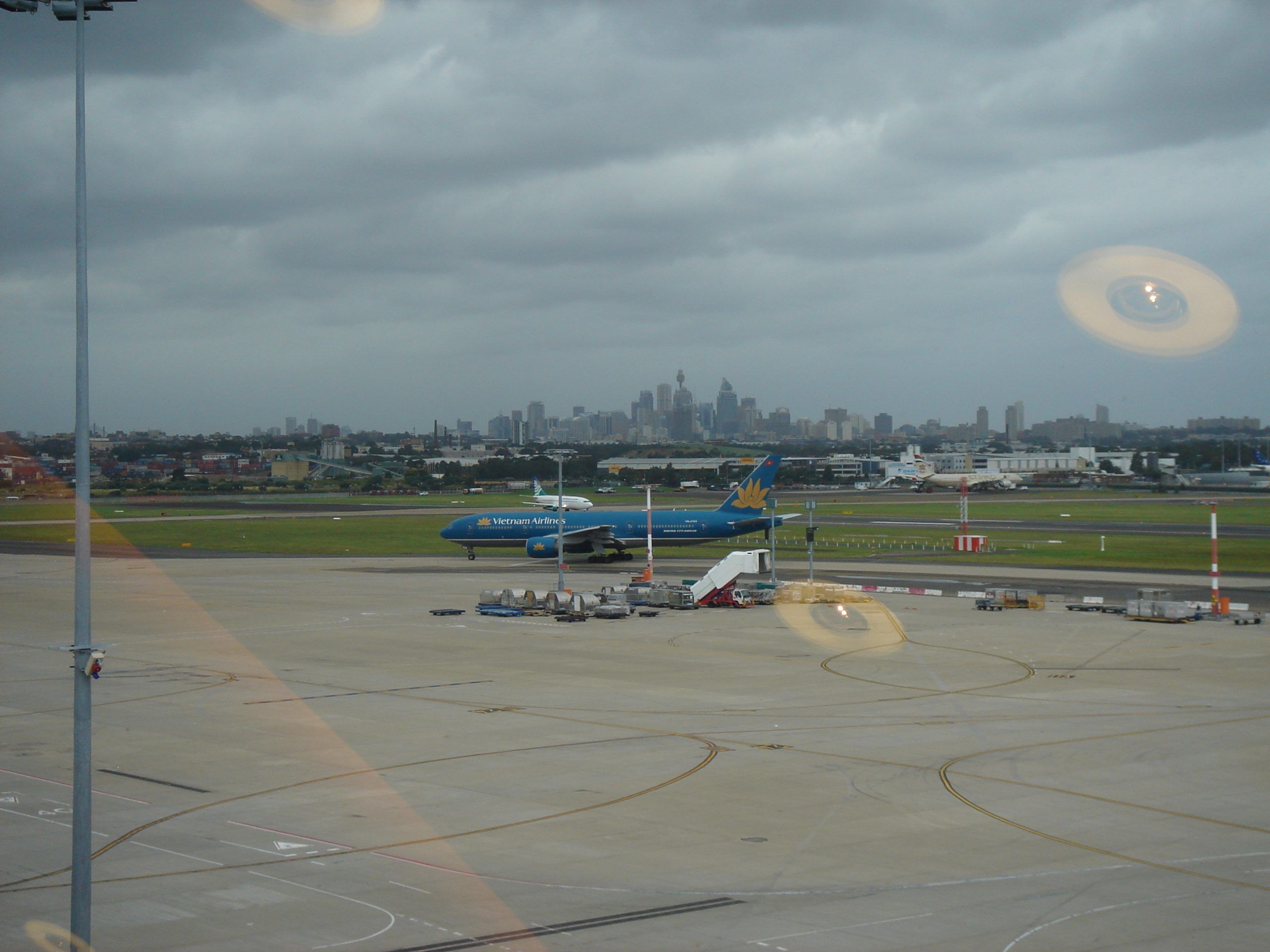 A view out the window of the Qantas lounge. There is a blue Vietnam Airlines plane sitting on the tarmac in the distance.