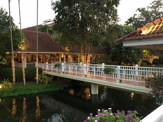 A walkway across the water between the dining room and a pagoda. The trees are festooned with lights