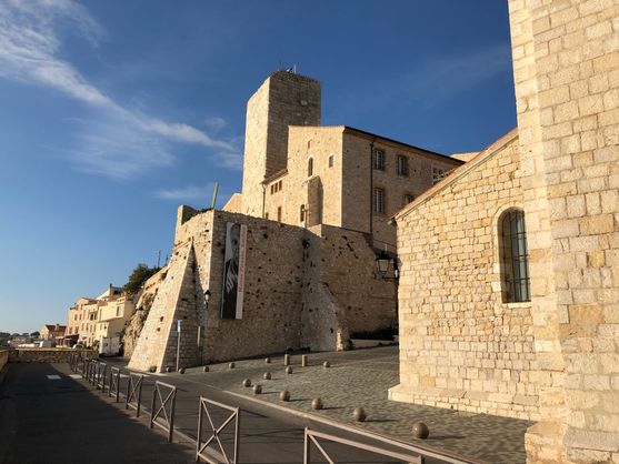 The exterior of the Picasso Museum in Antibes, an old angular building of yellow stone, which is glowing in the bright sunlight