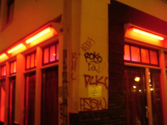 The blurry corner of a building, covered in graffiti, with red lit windows on each wall.