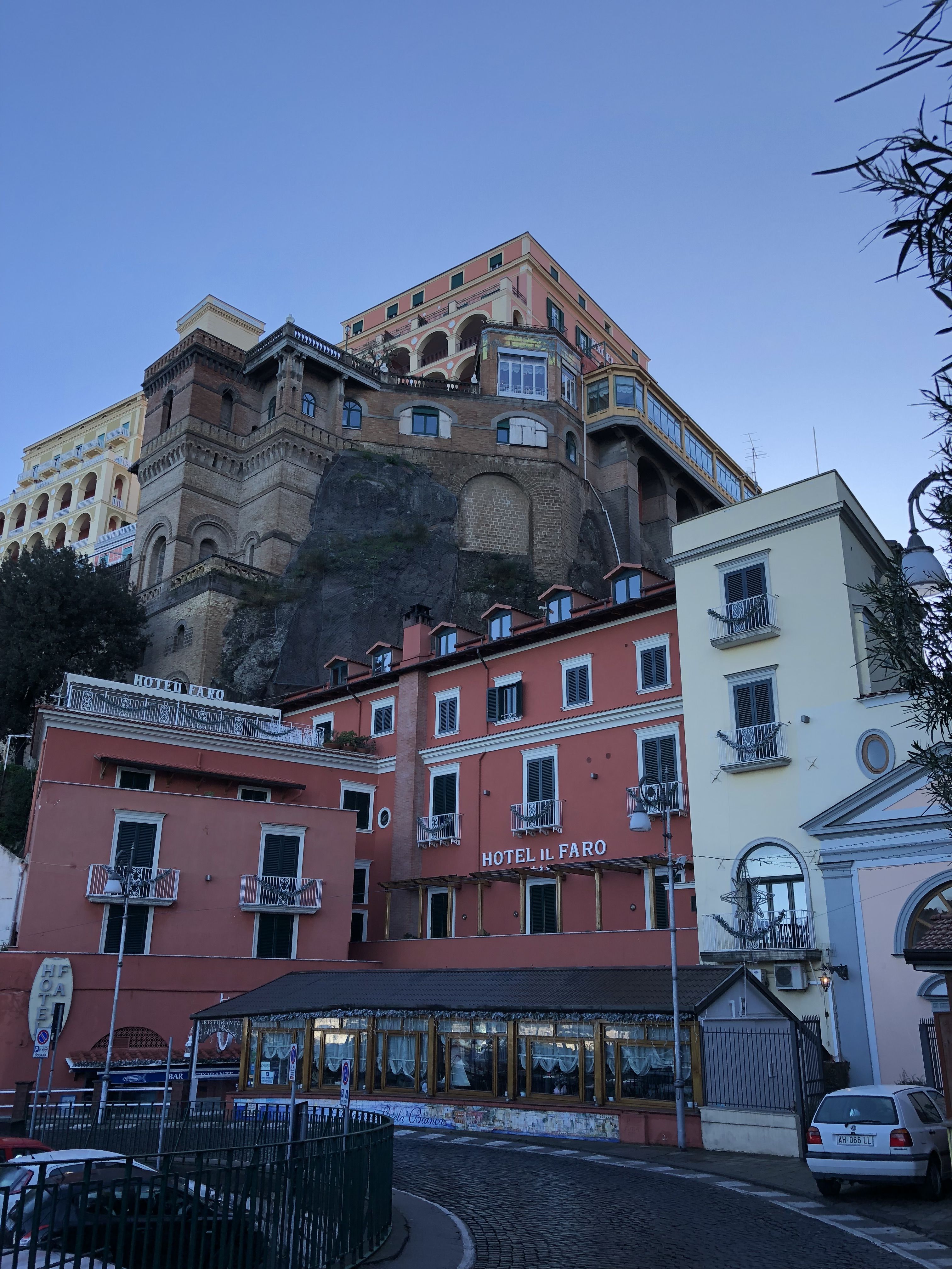 We're looking up a cliff, and we can see three hotels nearly perched on top of one another. The nearest, lowest one is called Hotel Il Faro and it has a restaurant out the front.
