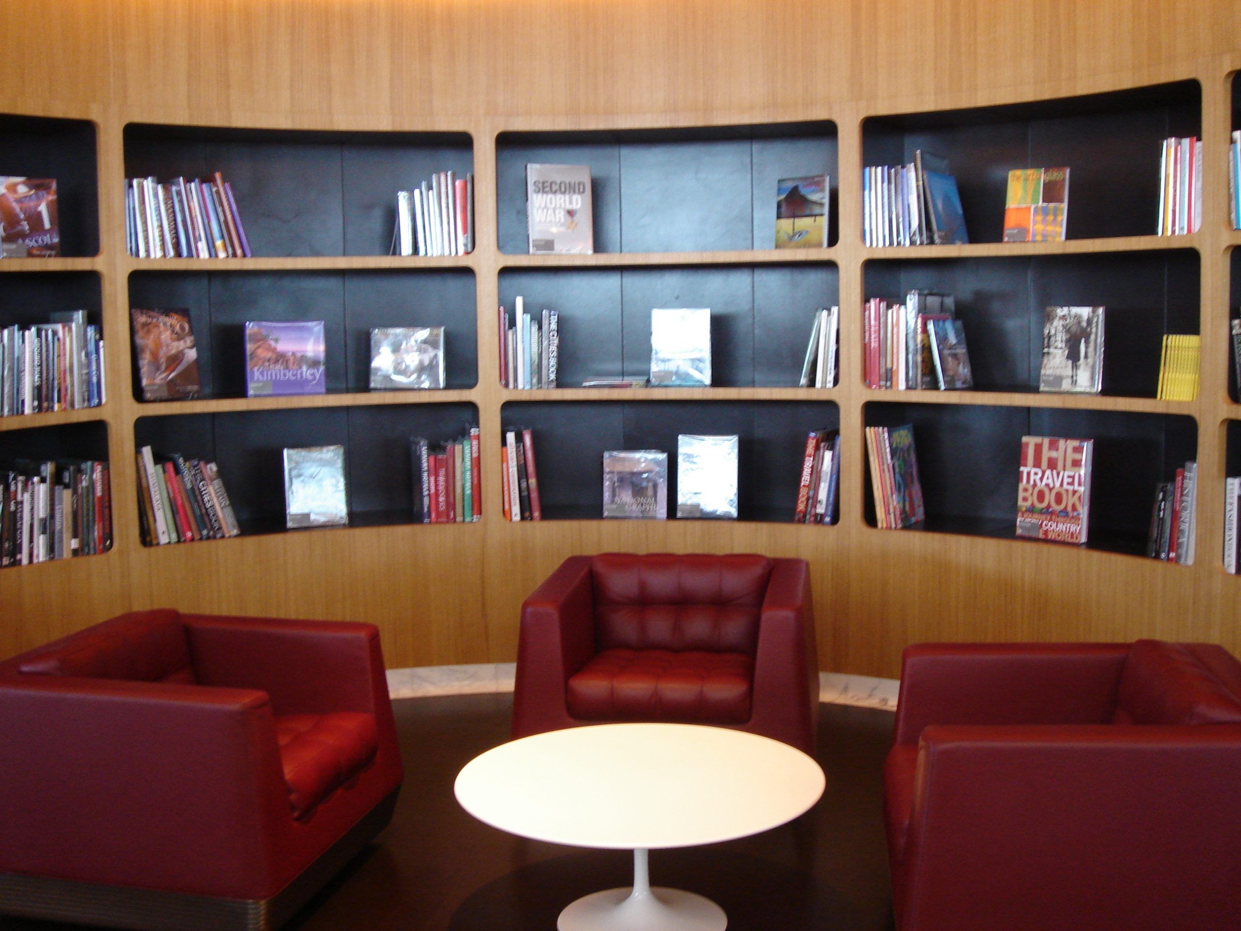 A round modernist table from the 1960s surrounded by couches; on the wall behind it are bookshelves with some books on display.